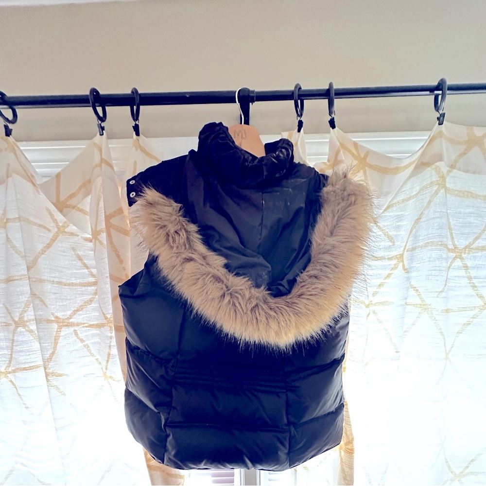 Black puffer vest in long length. Faux fur trim and silver chrome zipper.